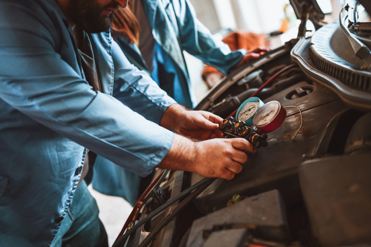 Två personer utför arbete med mobil AC i fordon under tillsyn enligt Kategori V